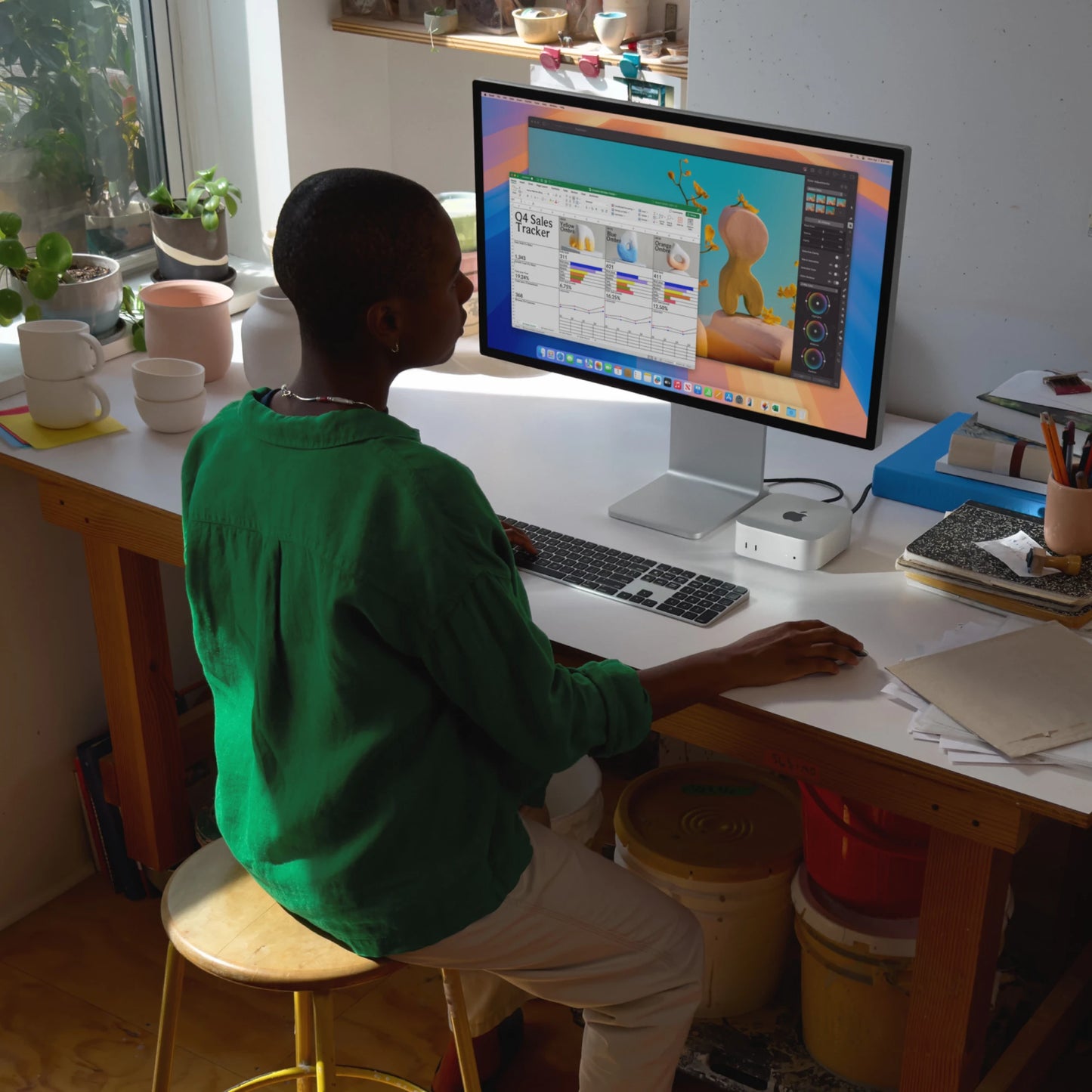 Person using Apple Mac Mini 2024 with external display and wireless keyboard in a creative workspace